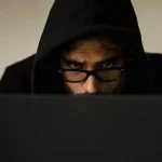 Hacker met hoody achter beeldscherm